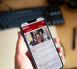 A man holding a phone and reading the news